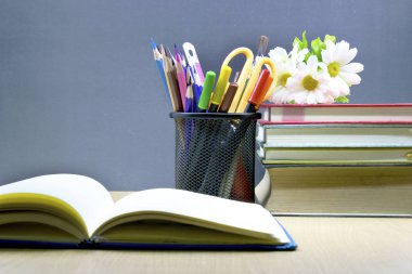 Masanın üstüne yığılmış koymak kalem ve kurşun kalem cetvel, fırça makas vardır,