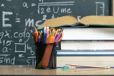 Blackboard matematiksel içerikli renkleri çeşitli ile yazılı. Öğretim harekete geçirmek için ön yan kitap yığılmış ve bir kalem dava vardır.