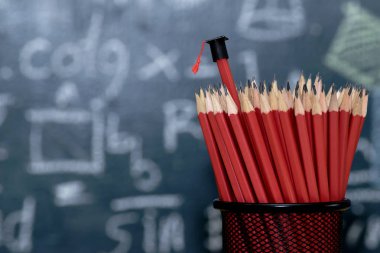 Mezuniyet kap giyim bir kalem, dairesel bir düzenleme, silgi, fon birçok kırmızı kalem seti olduğunu Blackboard matematiksel içerik ile öğretim uyarmak için renkler, çeşitli ile yazılı.