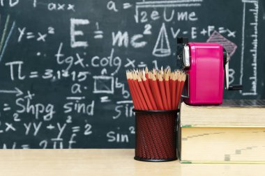 Birçok kırmızı kalem seti bir dairesel düzenleme, silgi, kalemtıraş masaya koymak, Blackboard matematiksel içerik ile zemin renkleri öğretim uyarmak için çeşitli ile yazılı.