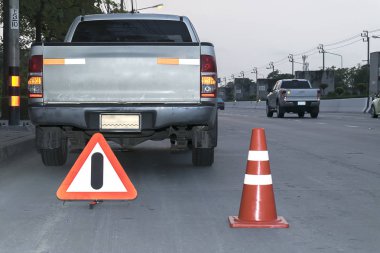 Yolda bir araba sorunlu çift yolda araba aşağı kırık, kırık araba, trafik koni ve Alarm işaretleri yakın genç kadın bir uyarı bu sinyal ayarlanır.