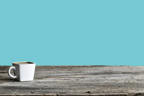 一杯白咖啡看起来像个正方形 放在带有天然木材的桌子上 背景是蓝色柔和的场面 它是世界上流行的工具 — 图库照片