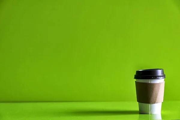 纸杯咖啡隔绝了绿色背景 玻璃周围有一张棕色的纸 防止热量 用于输入文本的空间 闪耀的光芒 — 图库照片