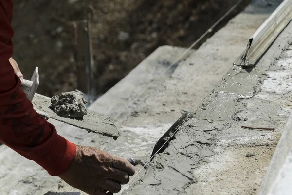 Hands Plasterer at work,Application of the textured plaster,staircase cement concrete structure in residential house building at construction site,Under construction reinforce concrete stair.