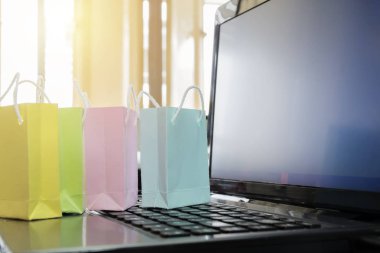 Online satış konsepti. Renkli kağıt torba laptop aittir. Pencere ve boş kopya alanı aydınlatma.