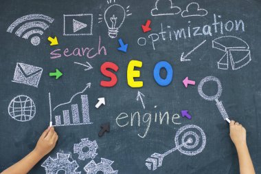 SEO, arama motoru optimizasyonu sıralaması konseptiyle alfabe kısaltma Seo çimento duvar kara tahta ortasındaki ve bilgisayar simgeleri, Web sitenize teşvik trafik fikrine işaret eden oklar.