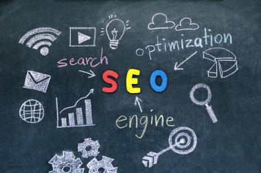 SEO, arama motoru optimizasyonu sıralaması konseptiyle alfabe kısaltma Seo duvar kara tahta ortasındaki ve bilgisayar simgeleri, Web sitenize teşvik trafik fikrine işaret eden oklar.