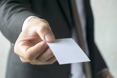 Beyaz bir kartvizit holding iş adamı. Beyaz kravat gömlek, siyah takım elbise giyiyor. kopya alanı.