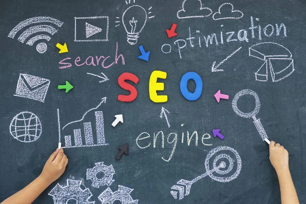 SEO, Search Engine Optimization ranking concept,with arrows pointing to alphabets abbreviation SEO at the center of cement wall chalkboard and Computer Symbols,the idea of promote traffic to website.