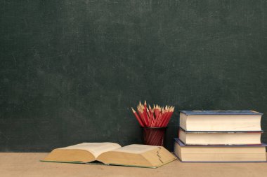 Açık başarı kavramı, kara tahta arka plan, yığılmış kitaplar ve kitap üzerinde kalem. Kırmızı kalem kalem tutucu koymak. Kendinizi geliştirmek öğrenmek.