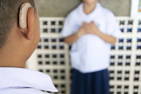 A boy wearing a hearing aid, talking to his friend. Have been encouraged. By communicating by hand.