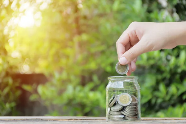 Nahaufnahme Hand Münze fangen in Glasflasche. — Stockfoto