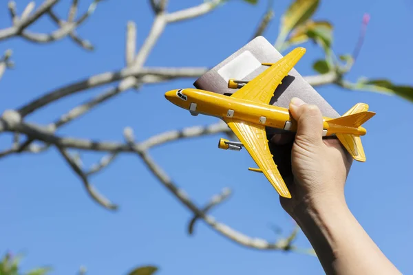 Reisekonzept. die Hand einer Frau, die einen Pass und ein Flugzeug hält — Stockfoto