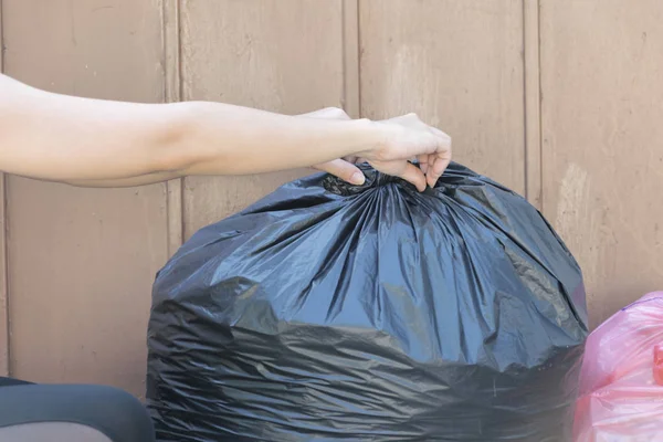 woman putting garbage bag into trash can. Bind it to make it eas