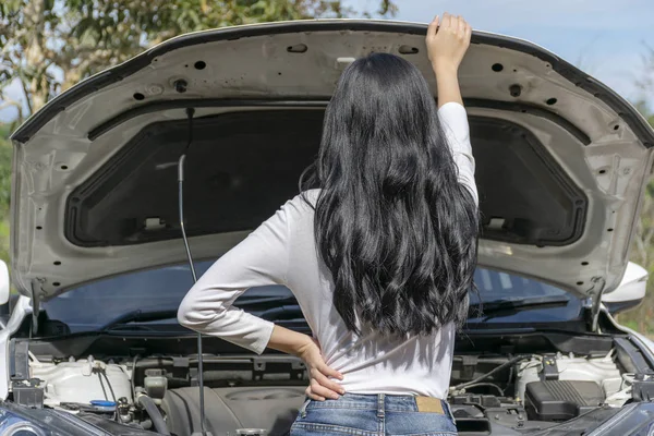 Young woman broken car and open hood during the trip on the road