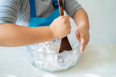 Asyalı bir kız, yemek yapmayı öğreniyor. Unu idare etmek için spatulaya yakın el, yemek pişirmeyi öğren.