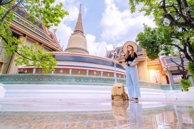 Yakışıklı Asyalı kadın Bangkok 'un Tayland' daki turistik merkezinin ortasında duruyor. Sırt çantası ve güzel Tayland tapınağı atmosferiyle birlikte.