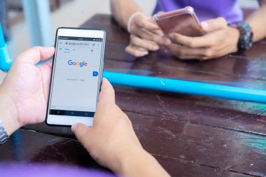 12 Haziran 2020 Bangkok, Tayland: Asyalı adamlar Google arama motorunda akıllı telefondan yazı yazıyor. Google dünyadaki en büyük internet arama motorudur..
