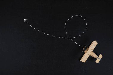 Seyahat konsepti. Kara tahta zemine yerleştirilmiş tahta bir uçak modeli.