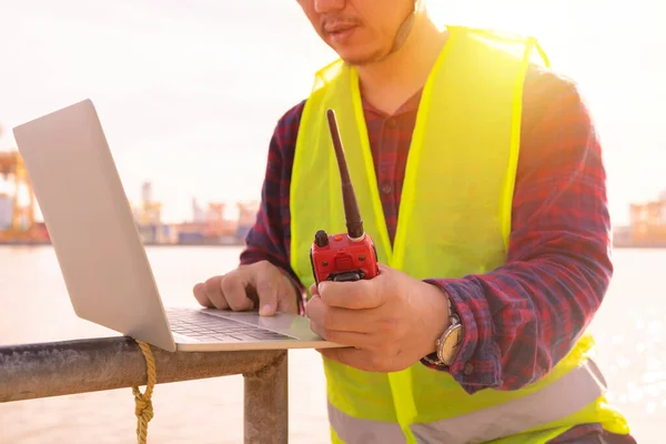 An engineer is using a tablet to work, he is at the shipping dock. Use radio communication for notifications and work orders.