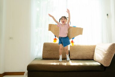 Oyuncak jetpack ile oynayan mutlu çocuk. Çocuk pilot evde eğleniyor. Başarı, yenilik ve lider konsepti. Oturma odasındaki kanepede.