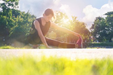 Formda ve sportif Asyalı kadınlar şehrin göbeğindeki gölgeli parklarda egzersiz için esneme hareketleri yapıyorlar.