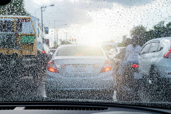 Street in the heavy rain. Water drops or rain in front of mirror of car on road or street. Driving in rain. Blurred background.