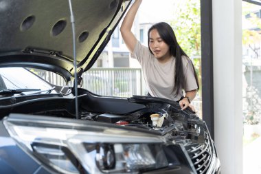 A beautiful woman checking the engine in her home. She is bent over the engine, looking at it intently may be checking the oil level, changing the oil filter, or performing other engine maintenance. clipart