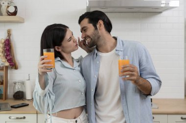 Modern mutfaktaki mutlu romantik çift gülümseyip birbirlerine bakarken taze portakal suyu bardakları, aşk konsepti, yaşam tarzı, ilişki, mutluluk, sağlık, aile..