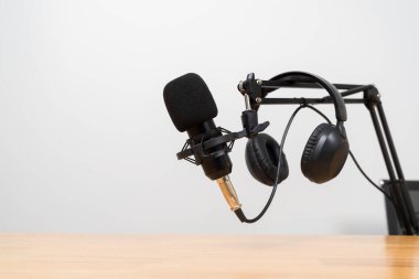 Ayarlanabilir bir kolda pop filtresi ve kulaklıklı profesyonel bir mikrofonu kapat, tahta bir masanın üzerine yerleştirilmiş, podcast, kayıt, yayın ve yayın kurulumunu temsil eden