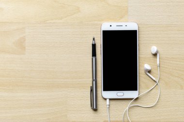 Boş ekran smartphone ile kulaklık ahşap masa üst köşesinde kalem var