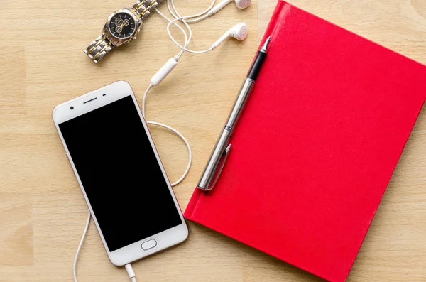 红色书盖子空白笔记本与笔在木桌和腕表耳机现代电话茶 — 图库照片