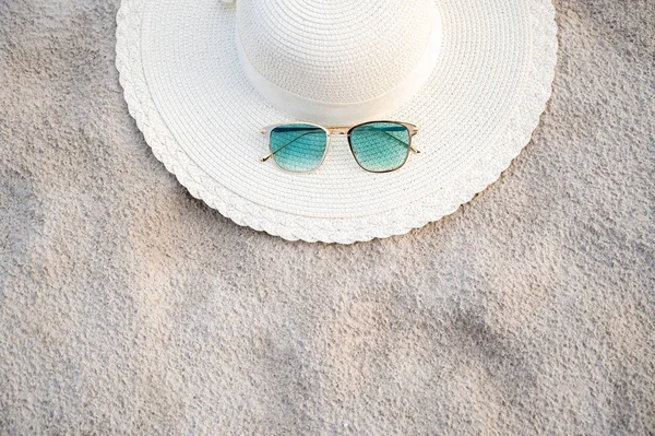 帽子と眼鏡は晴れた日に海の青い海のビーチに位置しています — ストック写真