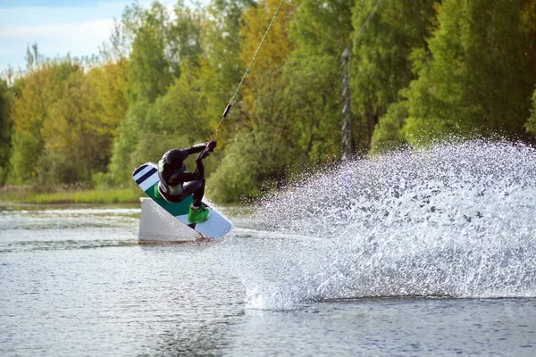 Wakeboardcu numaralar yapıyor. Düşük açılı adam gölde wakeboard yaparken..