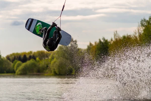 Wakeboardcu numaralar yapıyor. Düşük açılı adam gölde wakeboard yaparken..