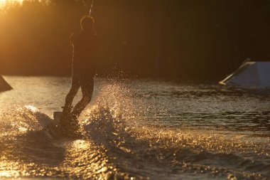 Wakeboardcu numaralar yapıyor. Düşük açılı adam gölde wakeboard yaparken..