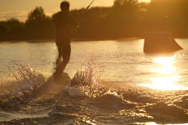 Wakeboardcu numaralar yapıyor. Düşük açılı adam gölde wakeboard yaparken..