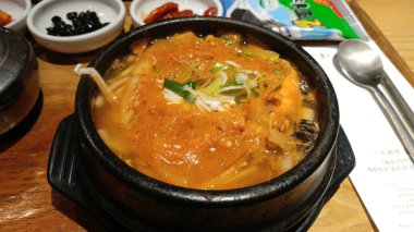 Arka planda mezeler olan geleneksel Kore çorbası.