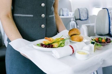 Uçuş görevlisi uçakta yemek servisi yapıyor.