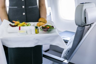 Uçuş görevlisi uçakta yemek servisi yapıyor.
