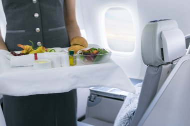 Uçuş görevlisi uçakta yemek servisi yapıyor.