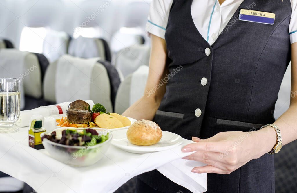 Mid section view of an air hostess carrying a tray of food