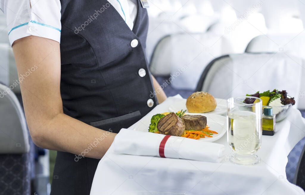 flight attendant serving meal in an airplane