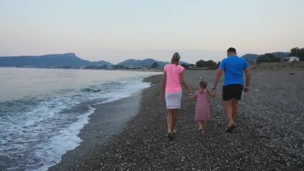 Счастливая семья, гуляющая по мраморному пляжу на закате — стоковое видео