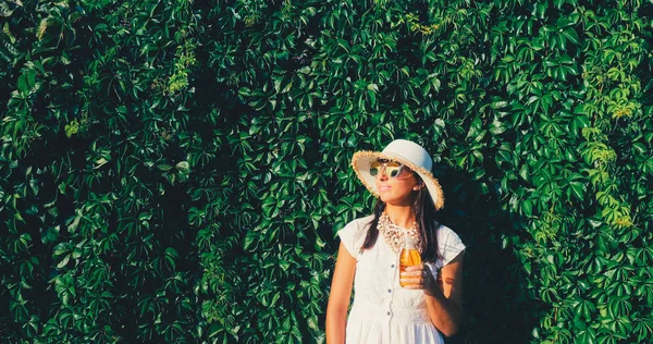 Bella donna con succo in piedi sullo sfondo della parete di uva selvatica — Foto Stock