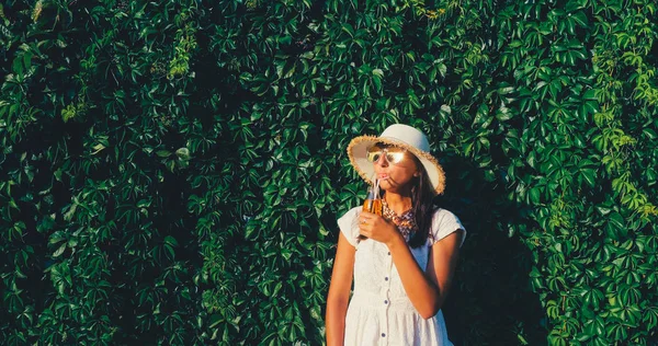 Beautiful woman with juice standing on the wild grape wall background — Stock Photo, Image