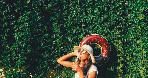 Bella donna con succo e ciambella galleggiante — Foto Stock