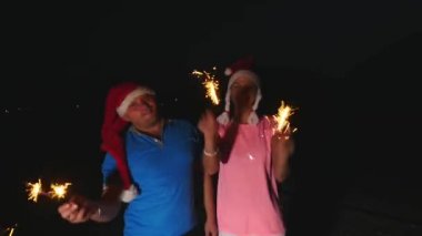 Genç erkek ve kadın Noel şapka Bengal ışıklarla dans