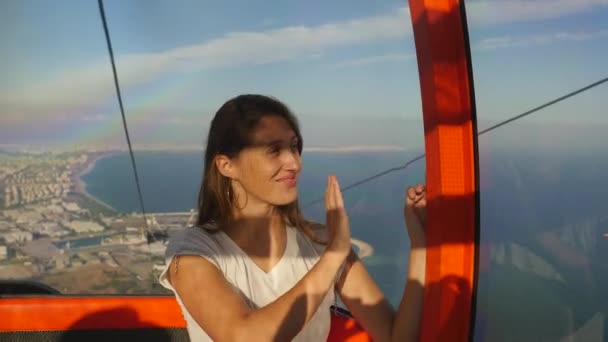Jeune touriste assise dans le téléphérique sur le chemin du sommet de la montagne — Video