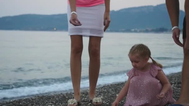 Père montre quelque chose à son enfant sur la plage de marbre au coucher du soleil — Video